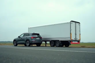 Remorque cargo blanche accrochée à un SUV gris foncé sur une route rurale française, vue latérale montrant la longueur totale de l'attelage